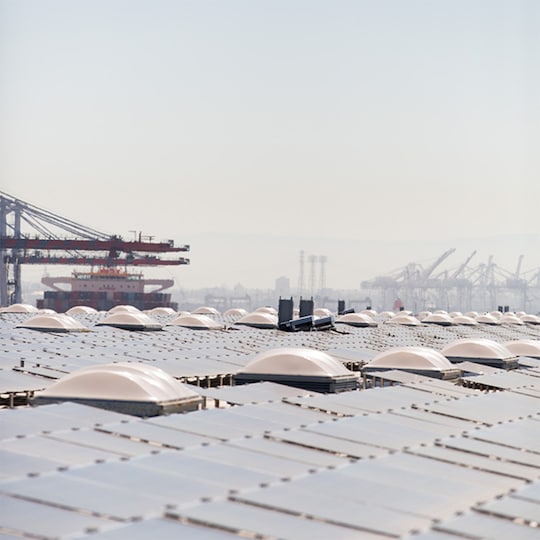 Large scale commercial rooftop solar panel installation stretching towards the horizon, featuring rows of photovoltaic panels.