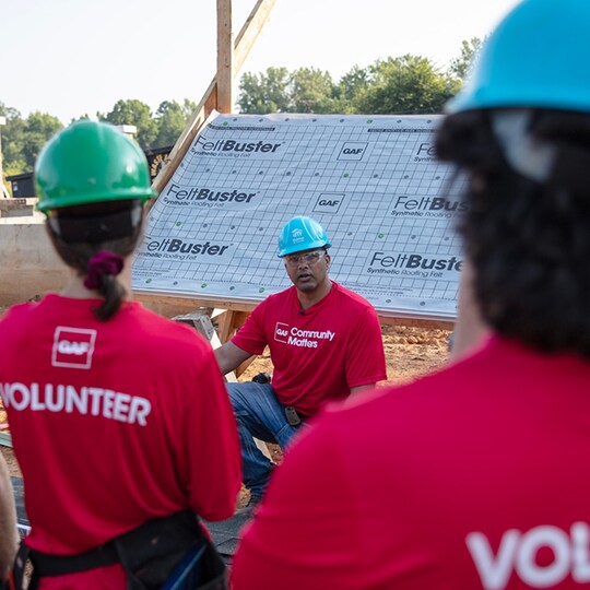 Roofing Academy trainer Gary Pierson speaking to volunteers at a construction site. 