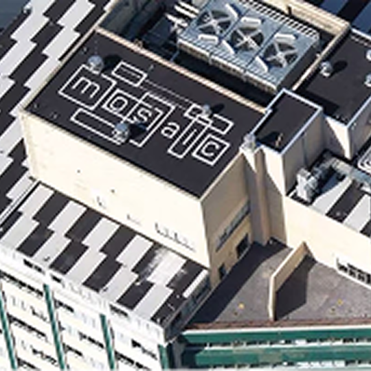 High-angle aerial view of a commercial building featuring a low-slope asphaltic roof system installation.