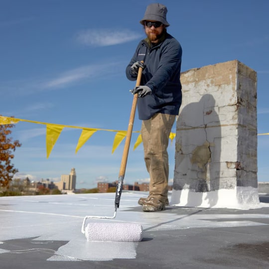 Contractor using a roof coating on a commercial roof