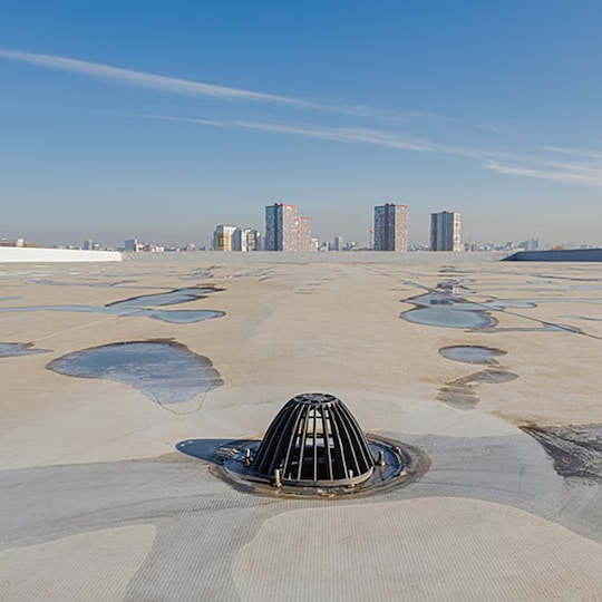 Commercial roof drain assembly on a white membrane roof designed for effective drainage and mitigating ponding water.