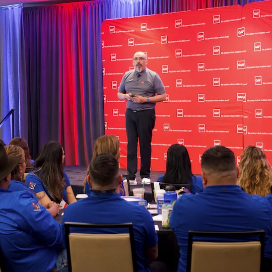 An audience of latino roofing professionals listens to Alan Lopez on the stage at the LIR conference