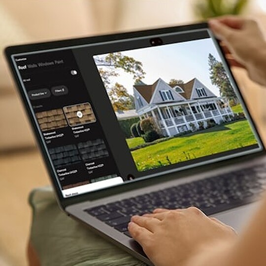 A homeowner’s hands hold open a laptop showing the virtual home remodeler on its screen.