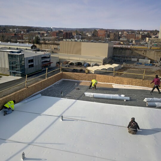 Aerial shot of GAF certified contractors installing a commercial roof system.