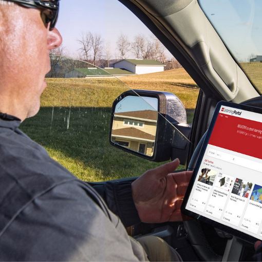 A roofing contractor in a truck with GAF Learning Portal open on a tablet