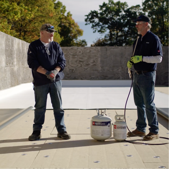 Dave Scott and Wally Brown setting up spray adhesive canisters on a commercial roof deck.