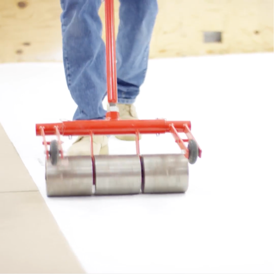 A GAF certified contractor using a weighted stand-up roller over self-adhered EverGuard SA TPO membrane.