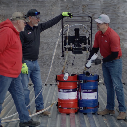 Dave Scott and Wally Brown discussing with a GAF certified contractor how to operate a TRUFAST adhesive pump rig to apply low-rise foam adhesive on a roof deck.