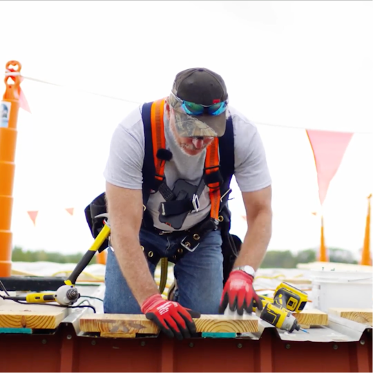 A GAF certified contractor in safety gear preparing a metal roof deck for a TPO retrofit installation.