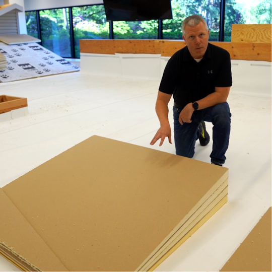 Andy Seymour, Director of Tapered Design, kneeling to demonstrate tapered insulation boards and roof slope design.
