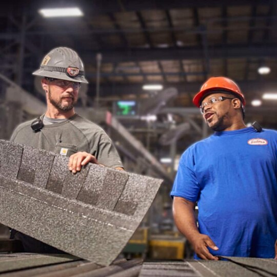 GAF roofing employee holding stack of roof shingles.