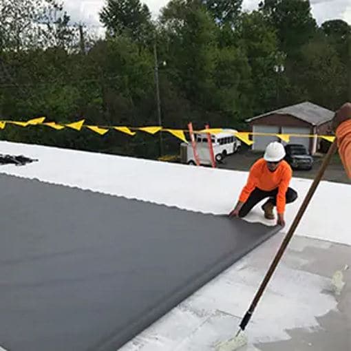 roofer laying a pvc membrane of pvc quick-lay adhesive