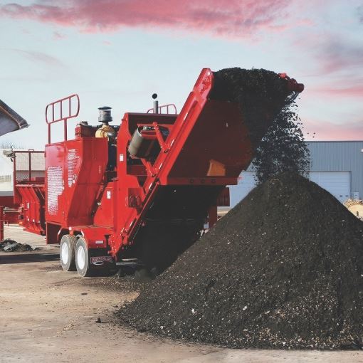Red machinery in asphalt shingle recycling plant.