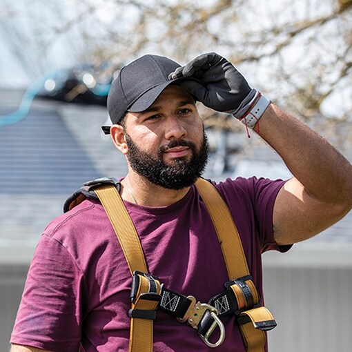 A roofing contractor at a job site where one crew is installing both asphalt shingles and solar shingles, creating the complete Timberline solar system.
