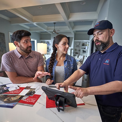 homeowners reviewing new roof options on a tablet with roofing contractor