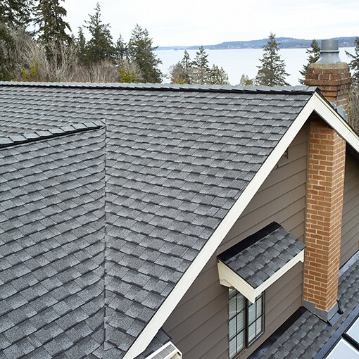 Aerial view of a newly installed, gray shingled roof on a house featuring severe weather-resistant, impact-resistant shingles manufactured by GAF.