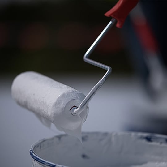 Roller brush rolling a coating on a roof