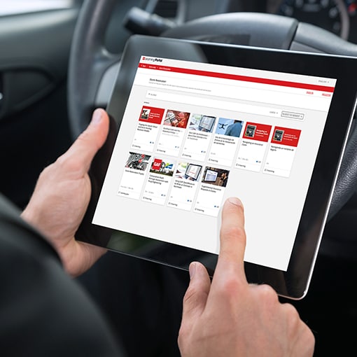 A contractor holds a tablet displaying available training classes for storm restoration roofing.