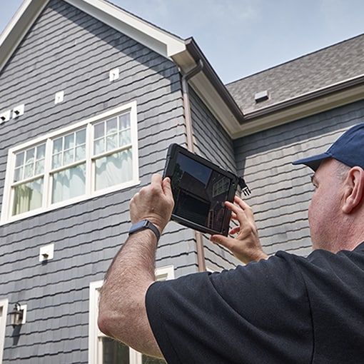 GAF certified contractor outside home holding tablet
