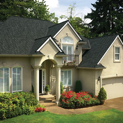 A beige home with charcoal Grand Sequoia® roof shingles by GAF that meet the criteria of the FORTIFIED™ Program.