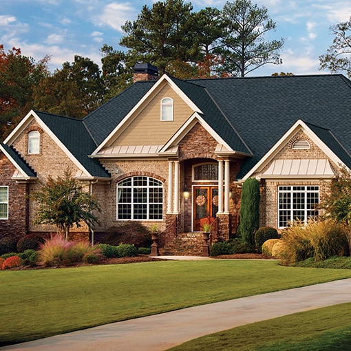 A light brick and beige home with charcoal Grand Sequoia® RS shingles by GAF that meet the criteria of the FORTIFIED™ Program.