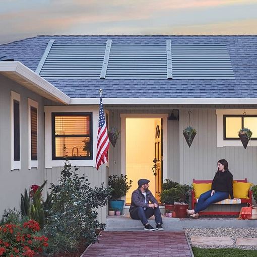 Homeowners on a porch of a home with a new GAF solar roof