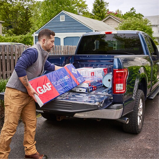 Roofer loading GAF Timberline HDZ shingles into his truck.