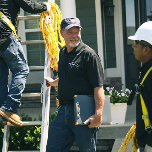 roofers talking in front of a residential home shingle installation
