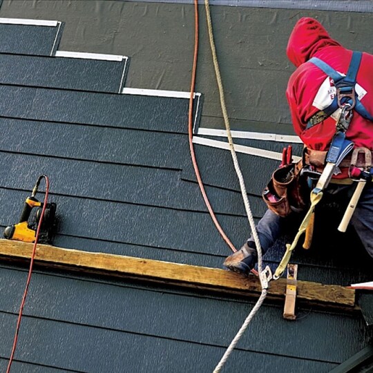 A metal roof system being installed on a home by a roofer.