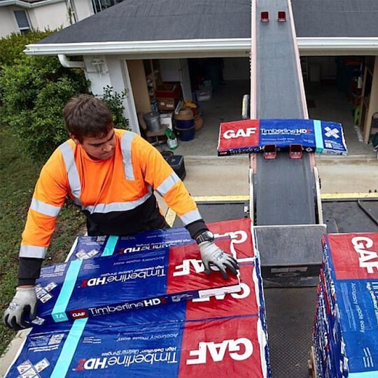Close up of a hammer, nails, shingles, and roof sheathing.