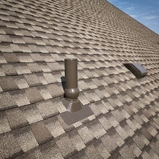 Side view of a metal chimney exhaust on asphalt roof with a cap