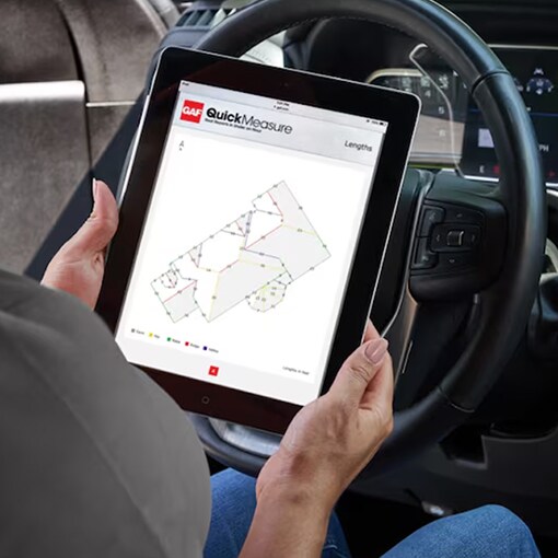 Hands holding tablet open to GAF QuickMeasure roof measurement tool