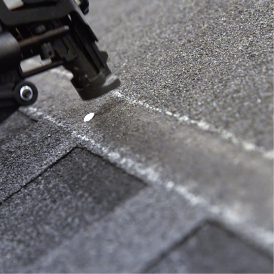 Close-up of a roofer’s nail gun securing shingles to a roofz