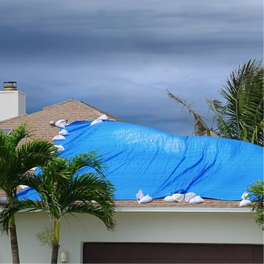A tarped roof under storm clouds illustrates the benefits of the WindProven Limited Wind Warranty in hurricane country.