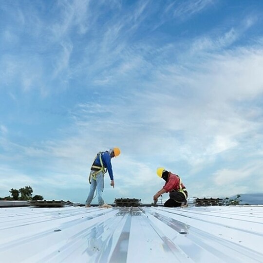 Two GAF certified commercial roofing contractors working on a commercial flat roof.