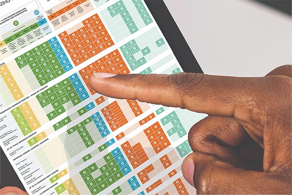 A person points to a color-coded chart on a tablet screen, which displays technical specifications and green building rating data.