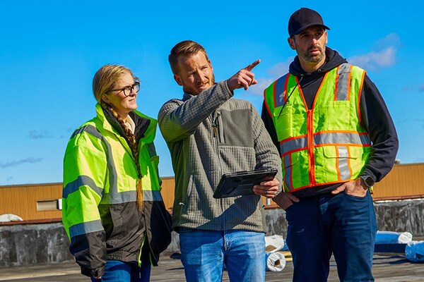 A GAF Territory Manager consulting with two GAF certified contractors on a commercial single-ply job site.