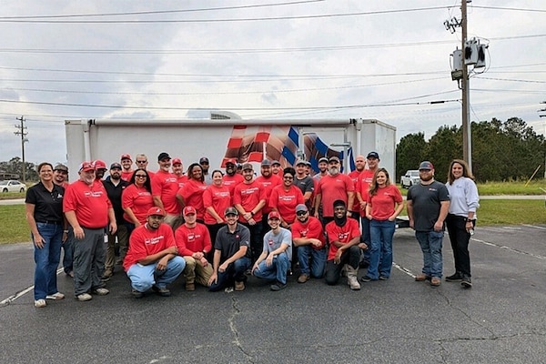 A group of GAF volunteers posing for a photo outside of a commercial plant. 