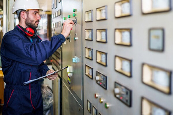 A military service member wearing a hard hat adjusts controls on an industrial panel during training for the GAF SkillBridge program.