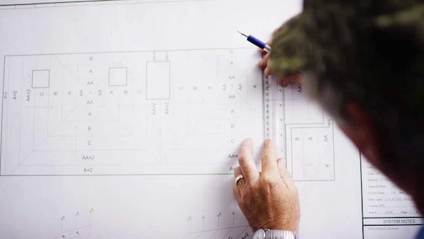 Human finger pointing to specific area in a GAF tapered design plan