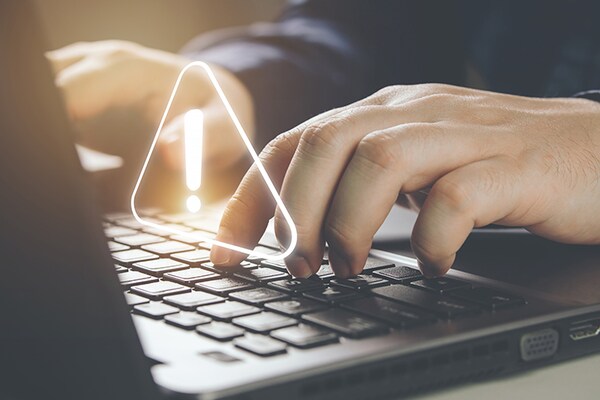 A person typing on a laptop keyboard featuring a glowing digital geometric overlay.