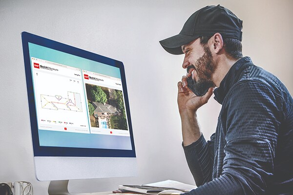 Side view of a man reviewing a computer monitor that displays a detailed roof diagram and an aerial photo from GAF QuickMeasure roofing reports.