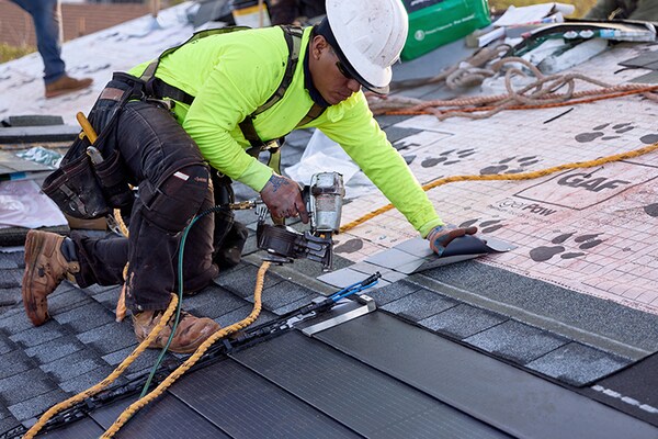 Roofers demonstrating solar roofing installation as part of training offered by GAF. 