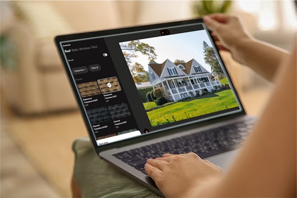 A homeowner’s hands hold open a laptop showing the virtual home remodeler on its screen. 