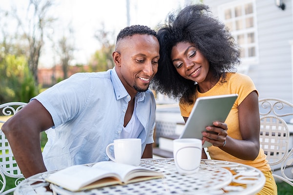 A homeowner couple looks at the energy production of their Timberline Solar Roofing System on their tablet device. 