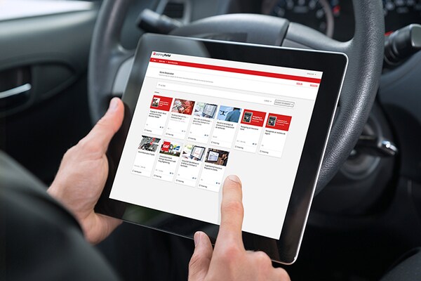A contractor holds a tablet displaying available training classes for storm restoration roofing.