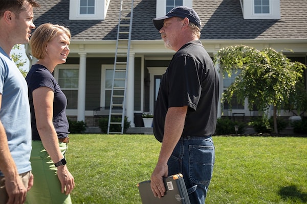 Roofing contractor outside home discussing roof insurance claim