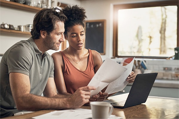 A couple reading their homeowners' insurance policy in the kitchen to check on roof damage coverage.