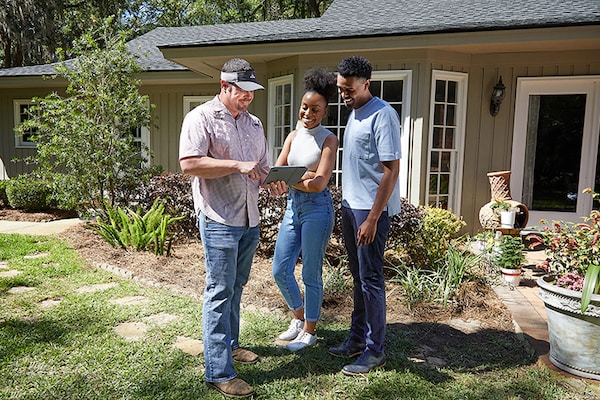 A GAF certified contractor explaining warranties documentation to a homeowner couple outside of their house.