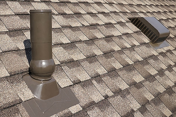 A close-up view of an asphalt shingle roof featuring GAF roof accessories that can help reduce water penetration. 